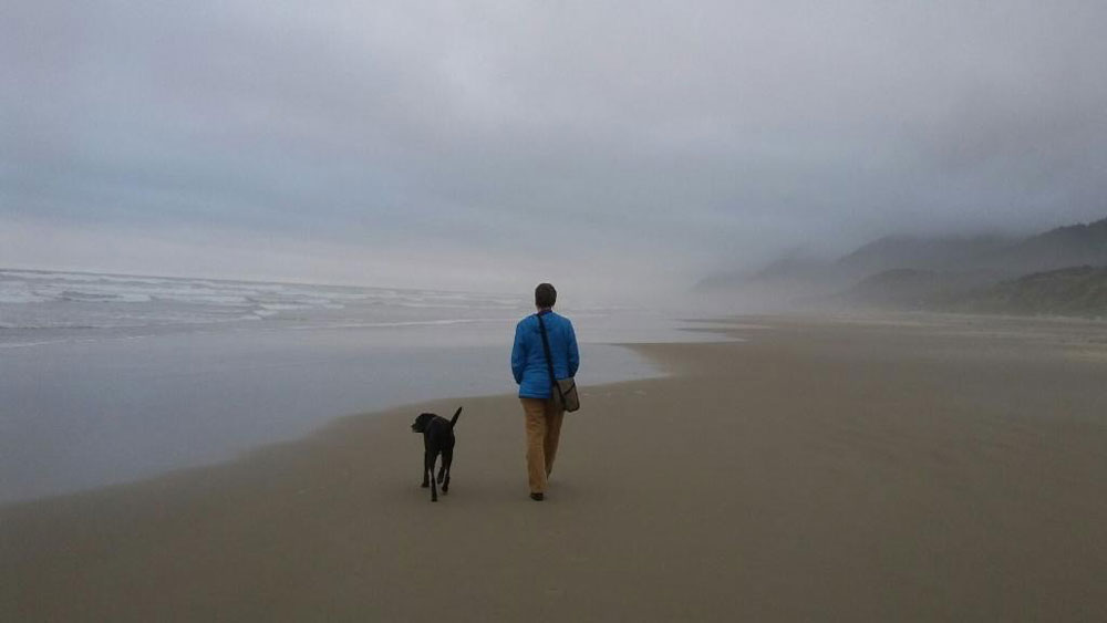 Artist Dawn Chandler walks along an Oregon beach with her sweet pup. Photo by Joe Beman.