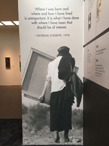 Museum exhibit banner of Georgia Okeeffe carrying a canvas outside