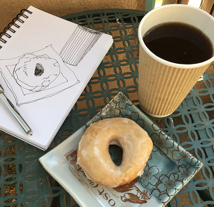 Sketchbook, coffee and a glazed donut.