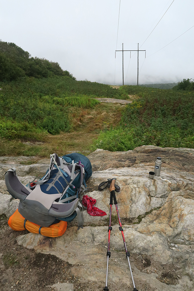 Pack and power-lines under a grey sky on the Long Trail, Vermont. Photo by Dawn Chandler. 