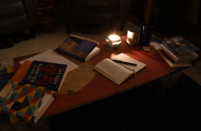 Delights: A low table arrayed with books, writing implements, and candlelight artist Dawn Chandler’s early morning creative space for reading, writing and contemplation. Photo by Dawn Chandler.