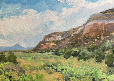 'Finding My Way to Pedernal’ original New Mexico landscape painting in oil by Santa Fe artist Dawn Chandler, featuring an expansive desert mesa, distant Pedernal peak, and lush green foreground beneath a bright, cloud-filled sky.